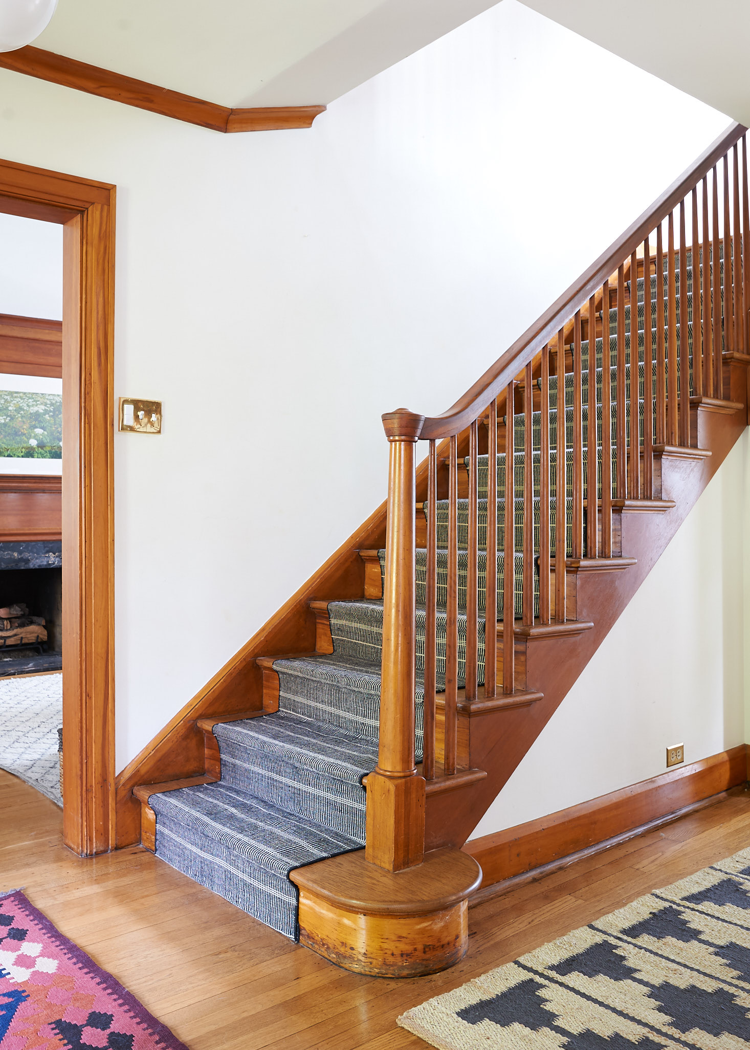 Black and neutral stair runner on wooden stairs.